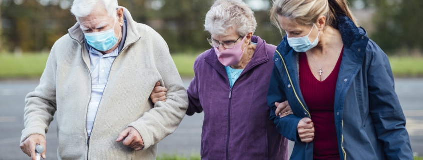 Eine jüngere Frau begleitet ein altes Ehepaar bei einem Spaziergang; Symbolbild: Getty Images / SolStock / Getty Images / E+
