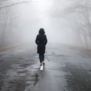 Einsame Frau läuft auf einer Straße in den Nebel - Symbolbild: Getty Images / gorchittza2012 / iStock / Getty Images Plus