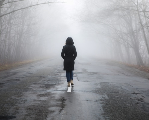 Einsame Frau läuft auf einer Straße in den Nebel - Symbolbild: Getty Images / gorchittza2012 / iStock / Getty Images Plus