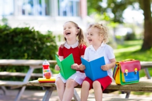 Zwei Kindergartenkinder sitzen lachend auf einer Bank. Symbolbild: Getty Images /FamVeld / iStock / Getty Images Plus