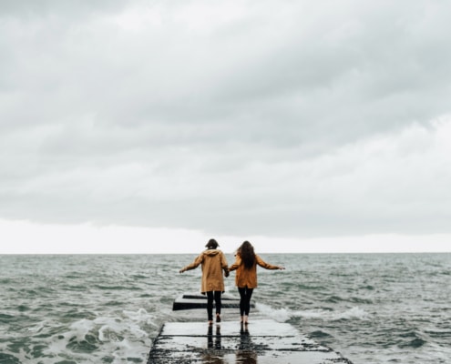 Ein Liebespaar läuft durch den Sturm in Richtung Meer. Symbolbild: Getty Images / dvulikaia