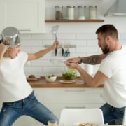 Ein Paar kämpft spielend in der Küche. Symbolbild: Getty Images / fizkes / iStock / Getty Images Plus