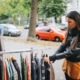 Eine junge Frau kauft in einem Secondhand-Shop Kleidung. Symbolbild: Getty Images / lechatnoir / Getty Images E+