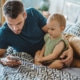 Ein Vater spielt vor seinem Kind am Handy. Symbolbild: GettyImages / svetikd / Getty Images E+