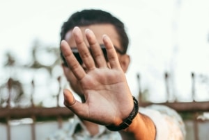 Ein junger Mann streckt seine Hand vor sein Gesicht.