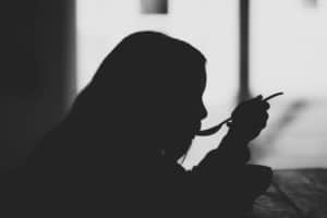Die Silhouette einer jungen Frau, die einen Löffel in der Hand hält.