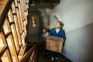 Ein Vater und ein Sohn laufen mit Umzugskartons eine Treppe hoch.