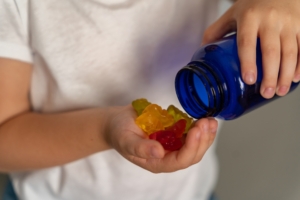 Ein Kind schüttet sich Gummibärchen aus einer Dose in die Hand.
