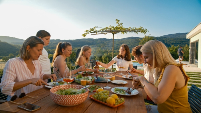 Eine Familie mit erwachsenen Kindern sitzt an einem großen Tisch und isst gemeinsam.