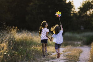 Zwei Kinder spielen glücklich auf einer Wiese.