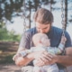 Ein einsamer Papa sitzt mit seinem Baby auf einer Schaukel.