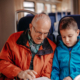 Alter Mann zeigt Jungen ein Buch im Zug