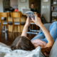 Teenager liegt zuhause auf dem Sofa und scrollt durch ihr Handy.
